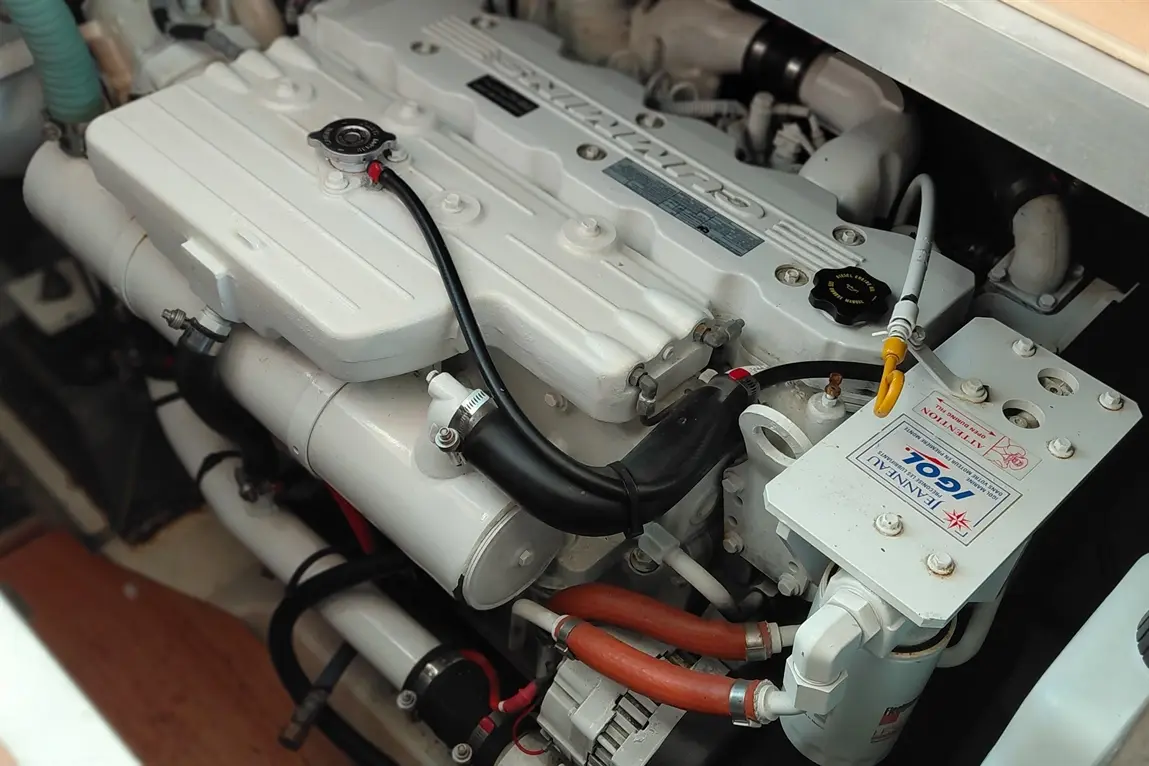 Close-up of a boat engine featuring a white valve cover, hoses, and a marked component labelled "Fennel 704".