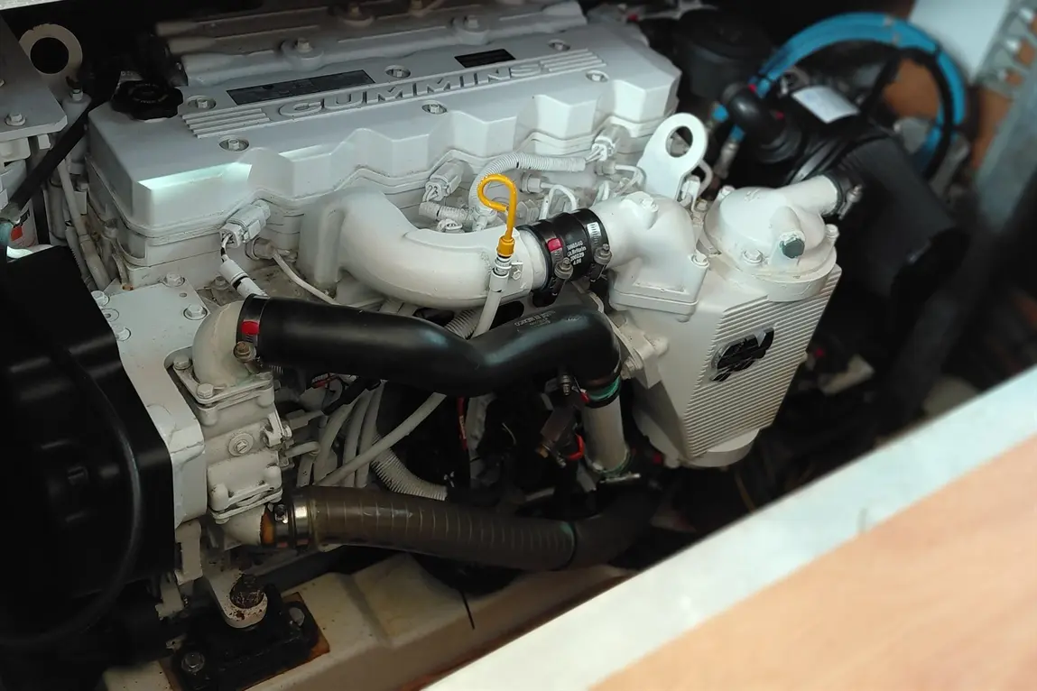 A close-up of a Cummins marine engine showing various hoses, a yellow dipstick, and components in an engine bay.