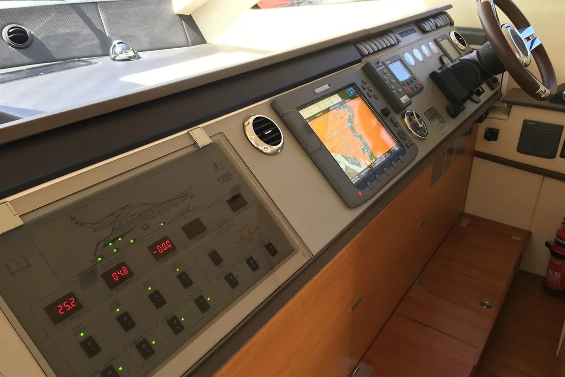 Boat control panel featuring navigation screen, gauges, and buttons for systems management in a bright, modern interior.