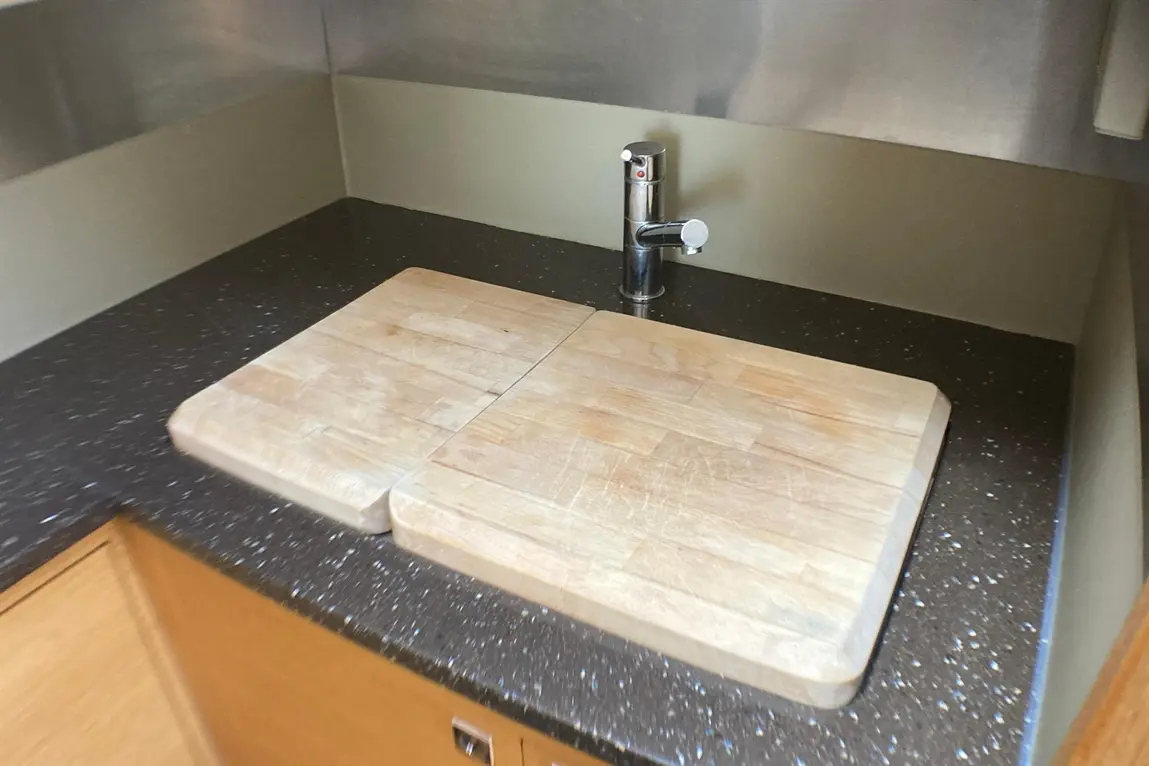 Wooden chopping boards on a dark countertop with a chrome faucet in a minimalist kitchen setting.