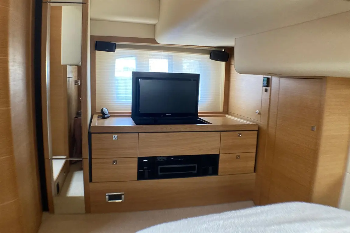 Modern interior with wooden cabinetry, a flat-screen TV, and decorative speakers next to a window with blinds.