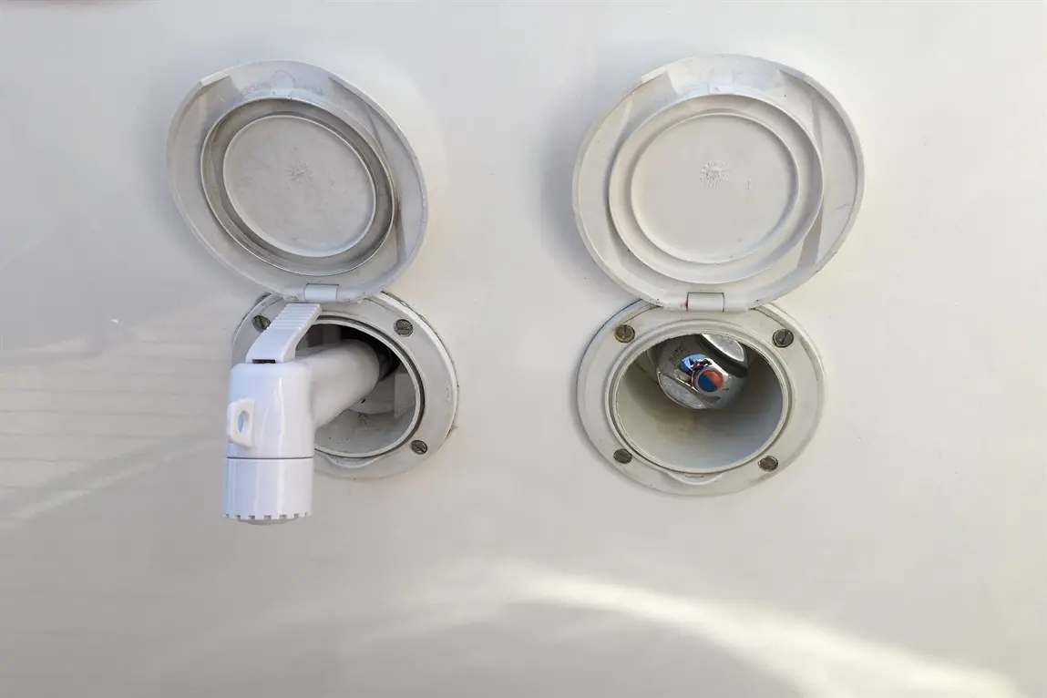 White wall-mounted compartments, one with a white connector partially inserted, the other with a metallic valve visible inside.
