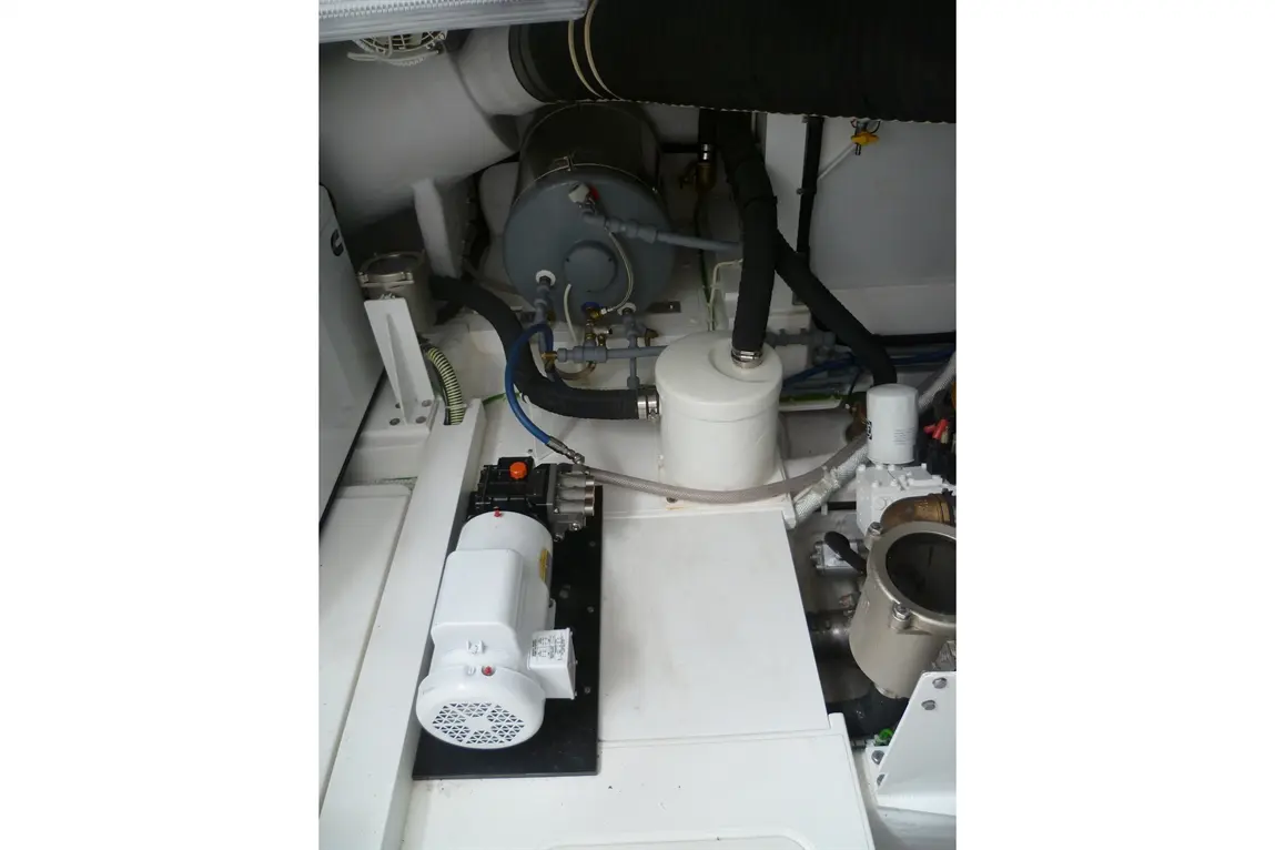 Engine compartment featuring a motor, fuel filter, and various hoses against a white interior background.