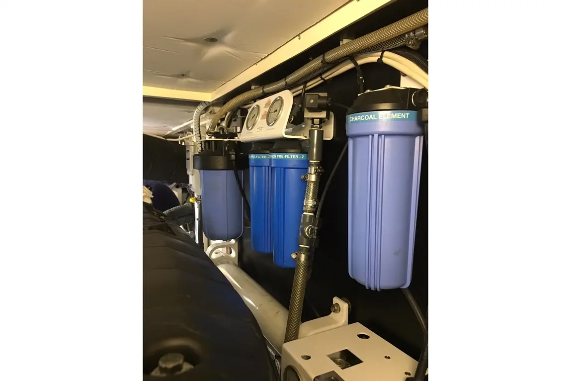 Water filtration system with three blue filters labelled 'CHARCOAL ELEMENT' and 'IRON PRE-FILTER-2', featuring connecting pipes.