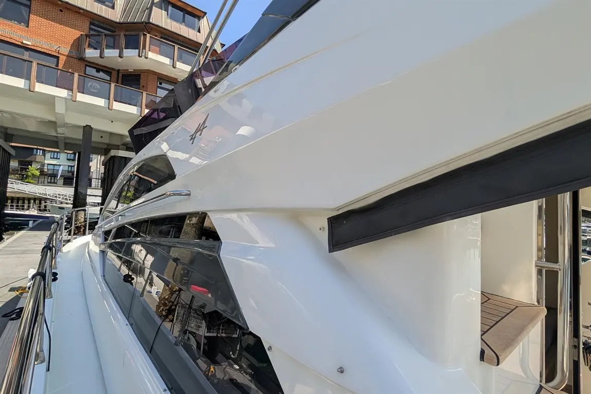 A close-up of a sleek white yacht by a marina, showcasing its polished exterior and modern design elements.