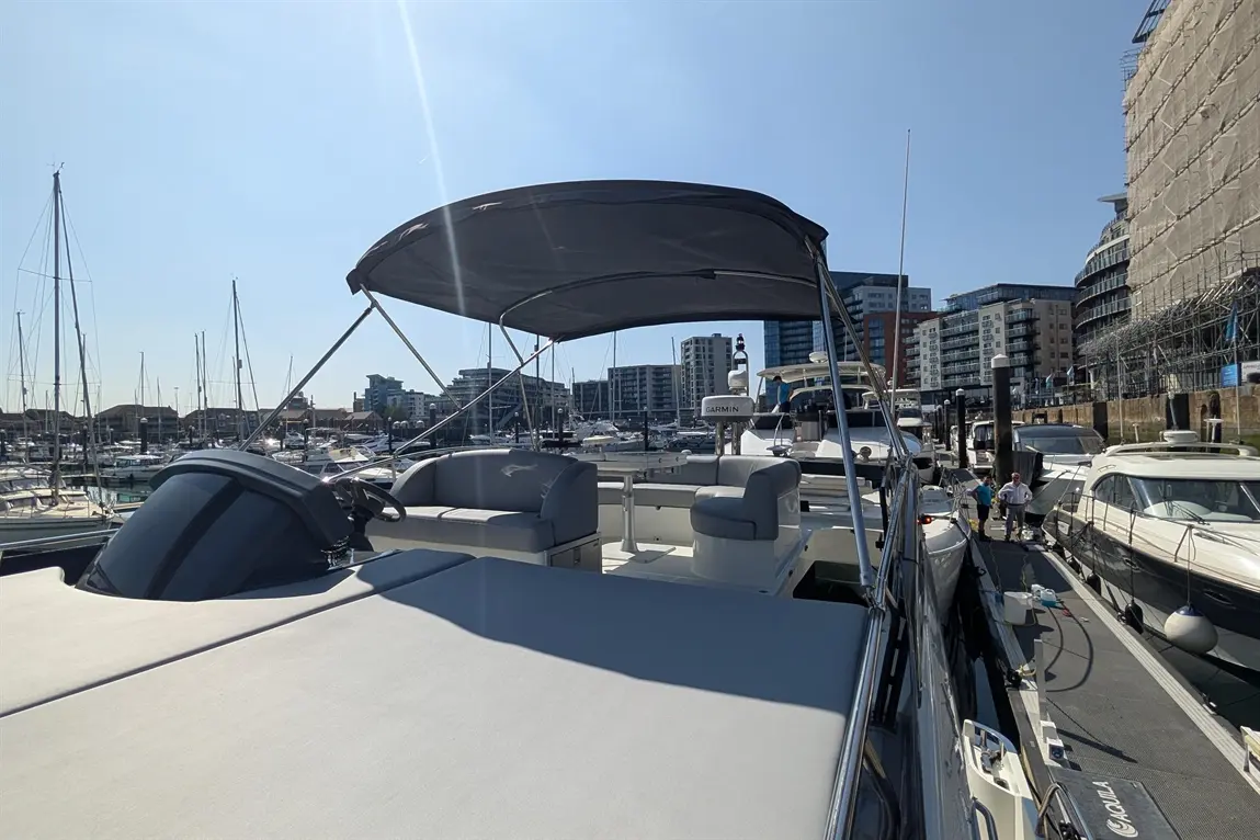 View from a boat at a marina, showcasing the cockpit area, with a sleek design and multiple yachts docked in the background.
