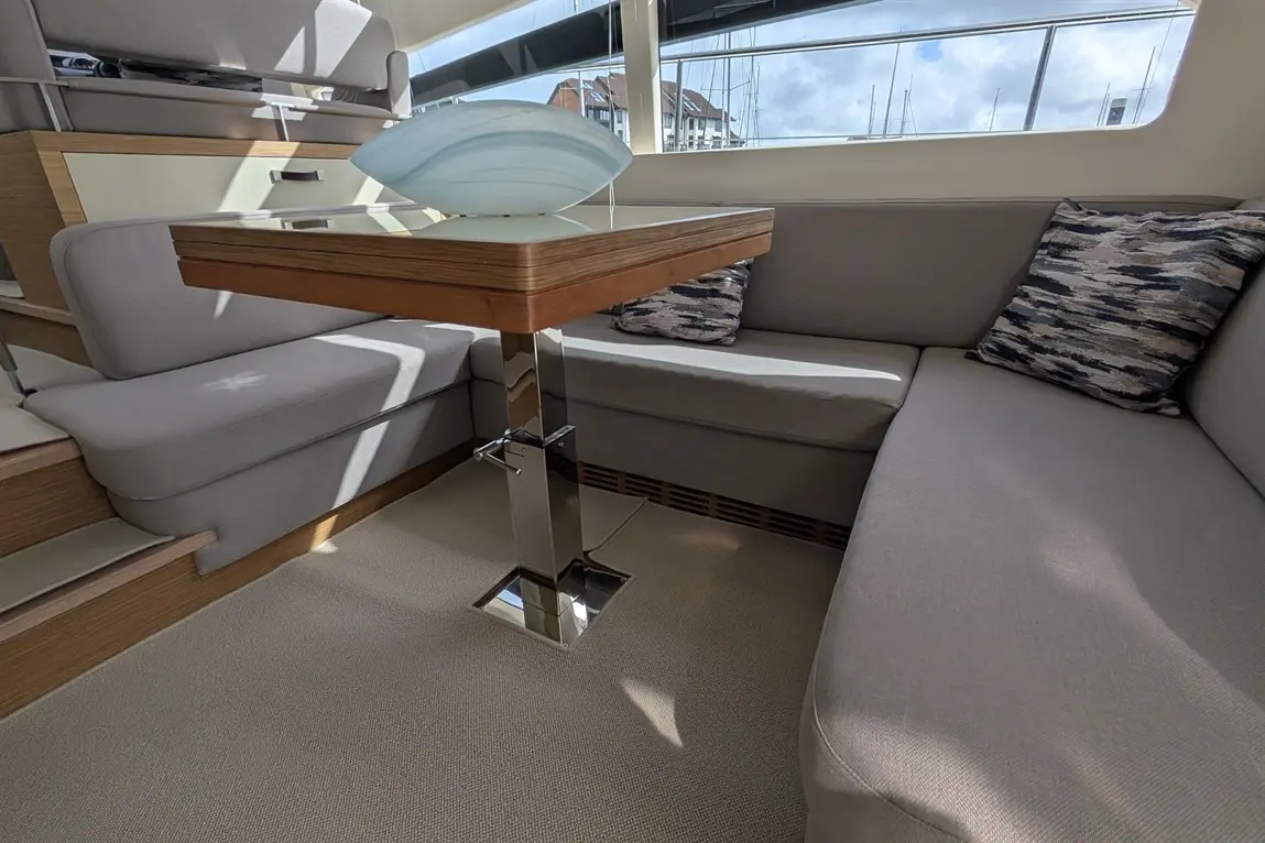 Modern yacht interior featuring a stylish table, grey seating, decorative cushions, and a light blue bowl.