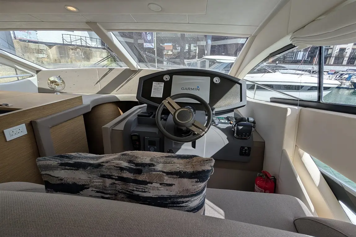 Modern yacht interior featuring a Garmin navigation system, steering wheel, and a plush cushion with a globe decor.
