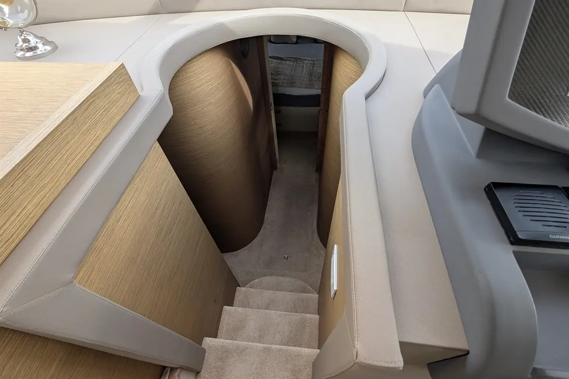 View down a curved staircase leading to a cabin on a boat, featuring soft carpeting and wooden walls.