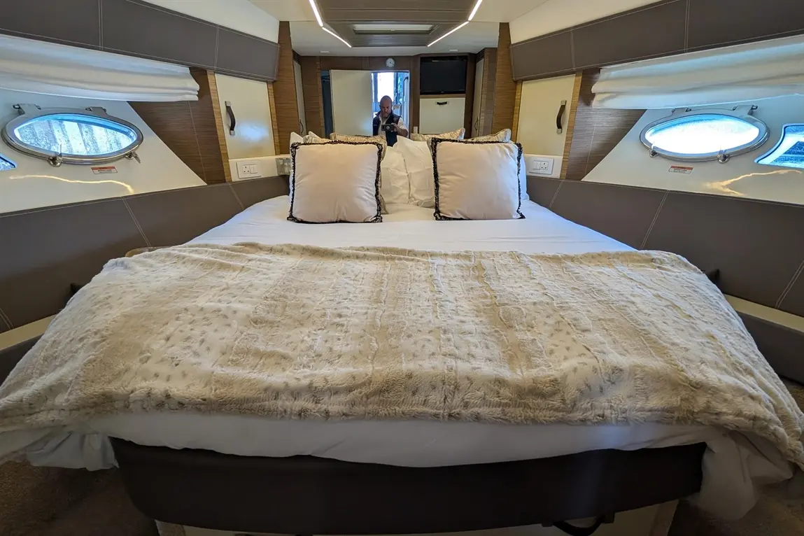 Luxurious bedroom interior featuring a large bed with pillows and a soft throw, surrounded by stylish furnishings and windows.