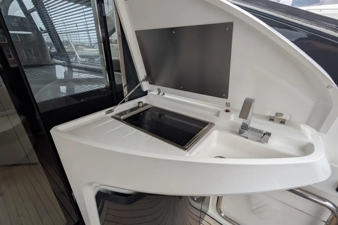 A modern boat kitchenette featuring a stainless steel grill, faucet, and sleek white storage surfaces.