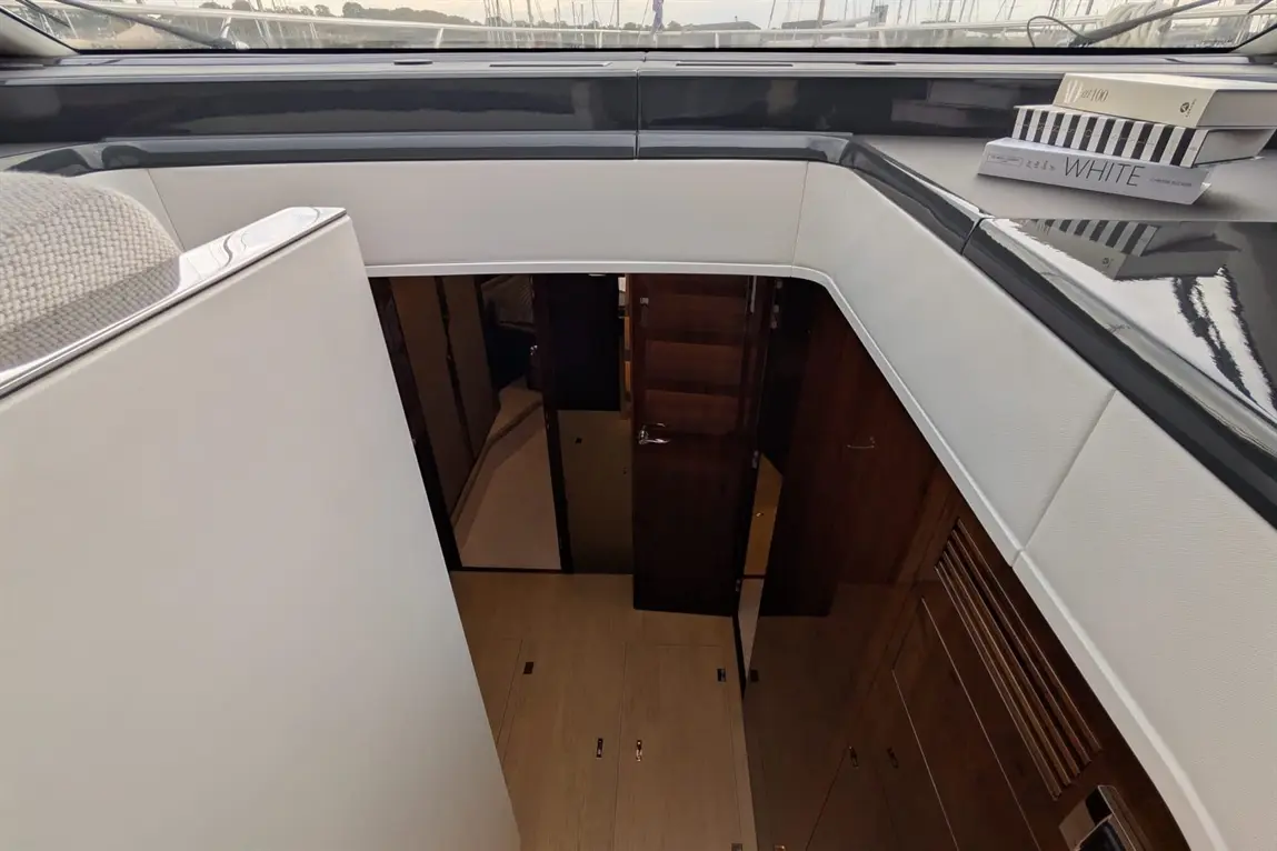 Interior view of a luxury yacht featuring polished wood finishes, doors, and a plush seating area, with books on display.