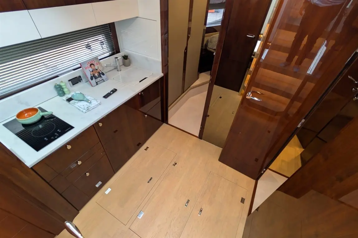 Modern kitchen with marble countertops, induction stove, and wooden cabinets; a cookbook and decorative items are visible.