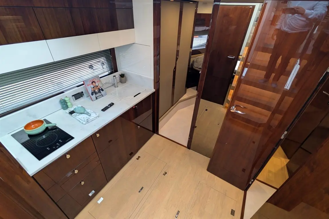 Modern kitchen interior showcasing a hob, sink, cabinets, and a magazine on the counter, with doors leading to living areas.