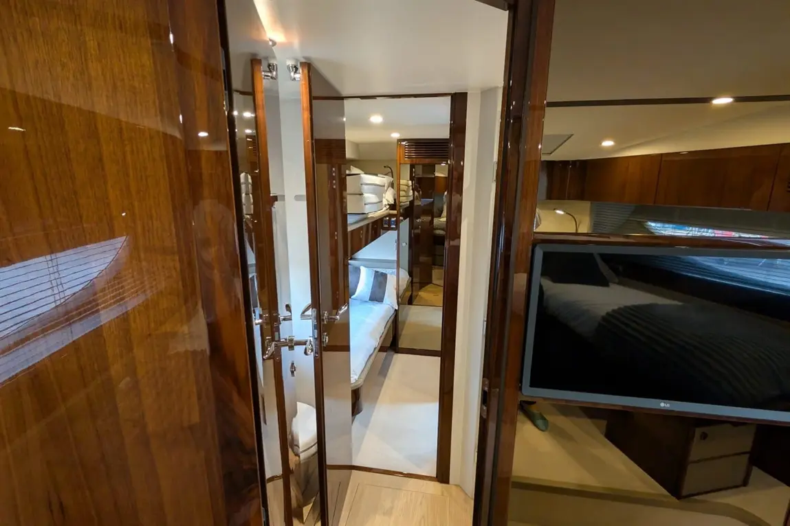 Interior view of a luxury yacht cabin, featuring polished wood finishes and a large flat-screen TV on the wall.