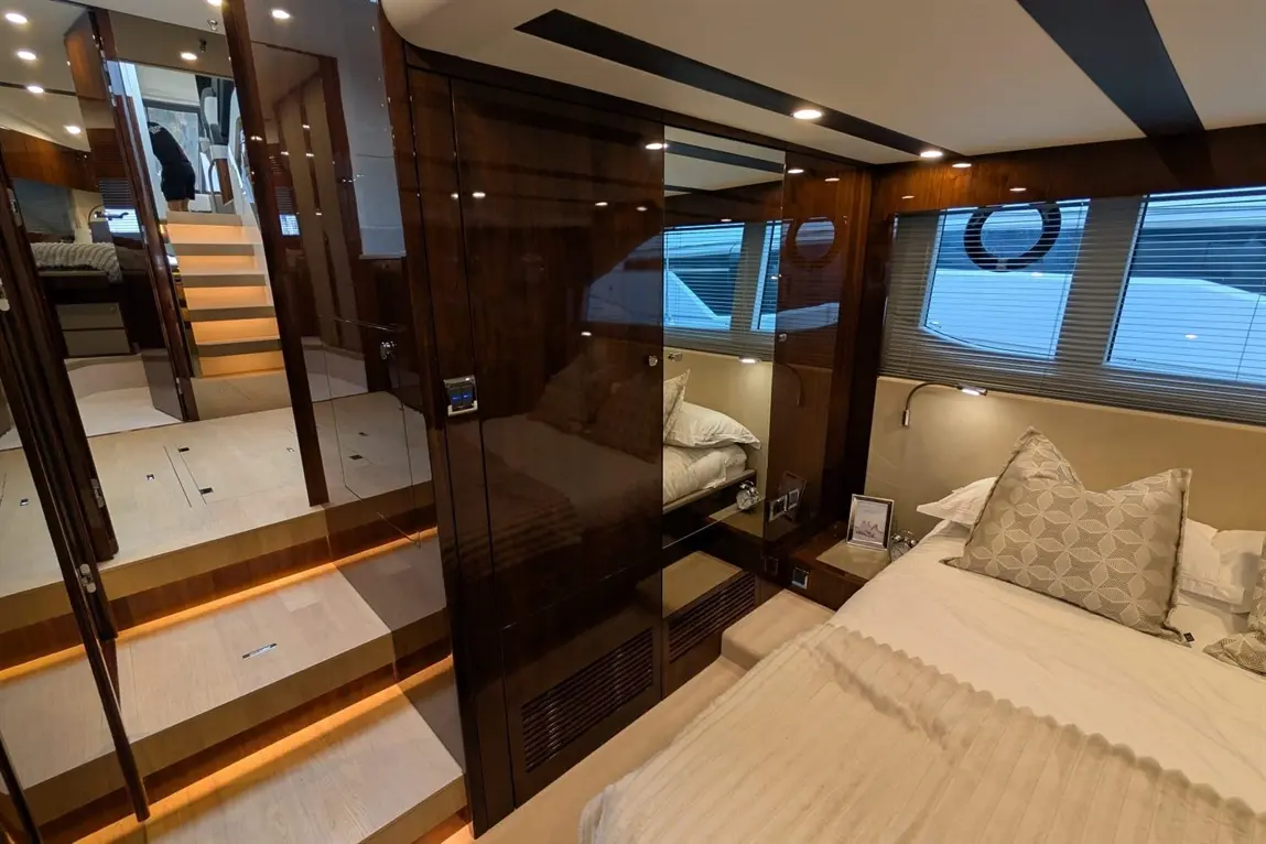 Luxurious boat interior featuring a bedroom, stairs with backlighting, and a polished wooden finish illuminating the space.