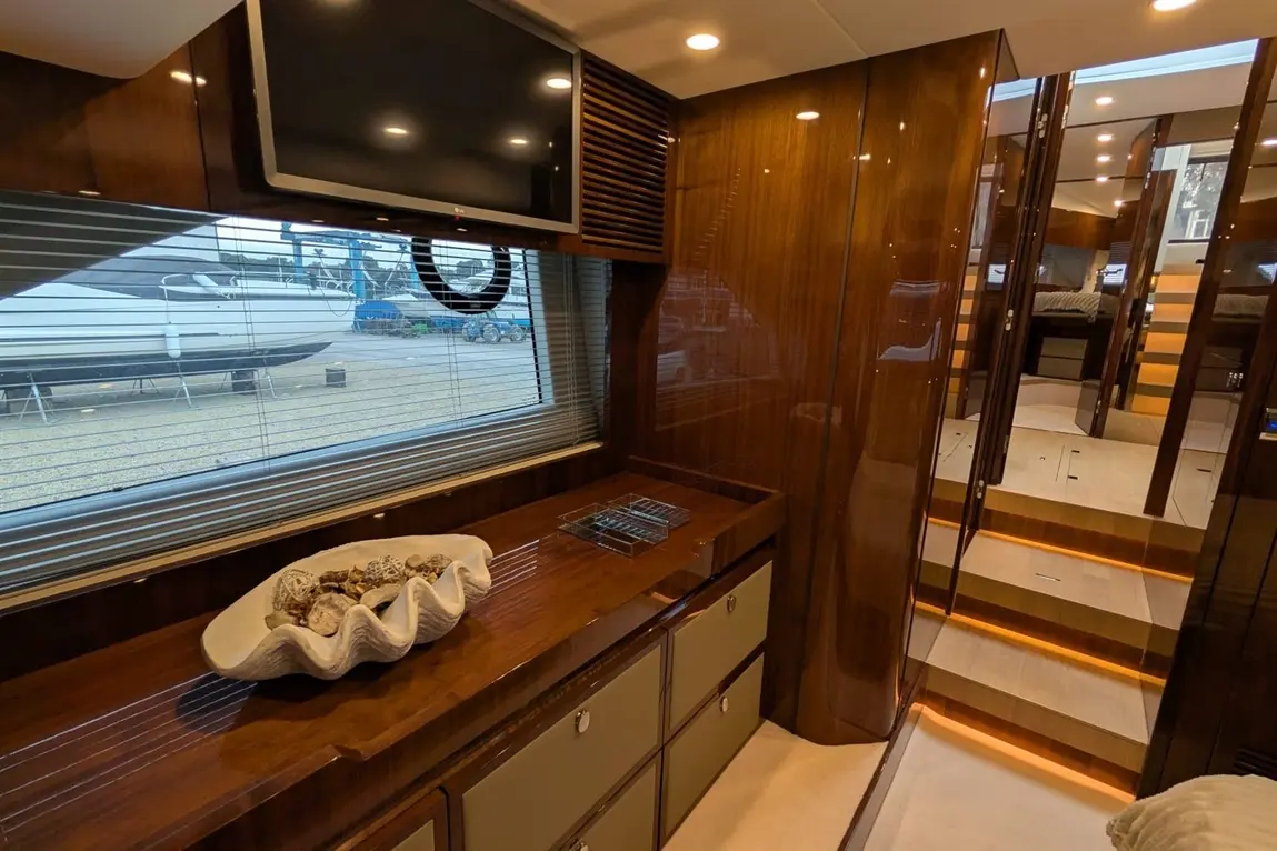 Luxurious yacht interior featuring a TV, wooden cabinetry, decorative shell bowl, and illuminated steps leading to the cabin.
