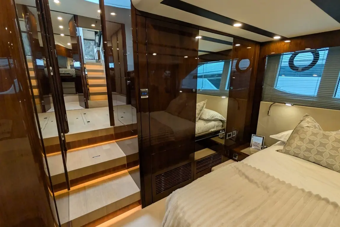 Modern yacht interior featuring a stylish bedroom, wooden steps, and luxurious furnishings, with muted lighting and decor.