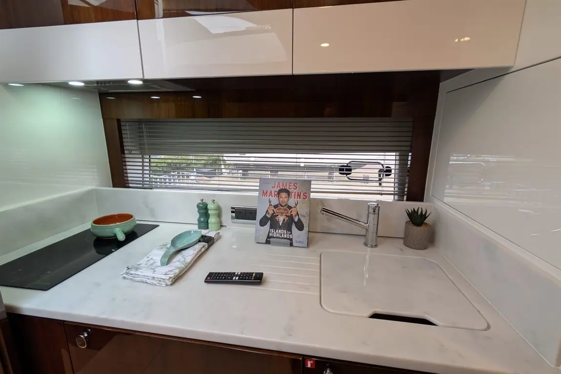 Modern kitchen with a marble countertop, cooking utensils, a cookbook by James Martin, and green decorative elements.