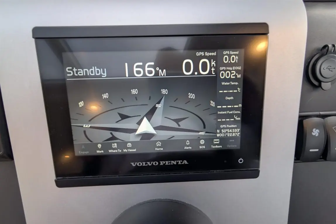 Volvo Penta display showing GPS speed, coordinates, water temperature, depth, and navigation compass on a marine control panel.