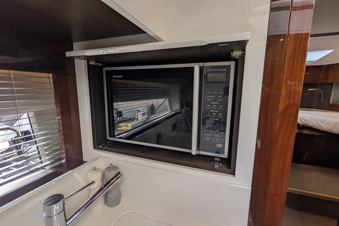 A built-in Sharp microwave with digital controls is seen in a modern kitchen setting, alongside salt and pepper shakers.