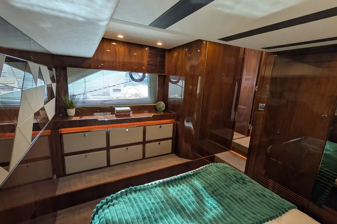 Modern luxury bedroom with wooden panels, green bedding, and stylish storage, featuring natural light and contemporary decor.