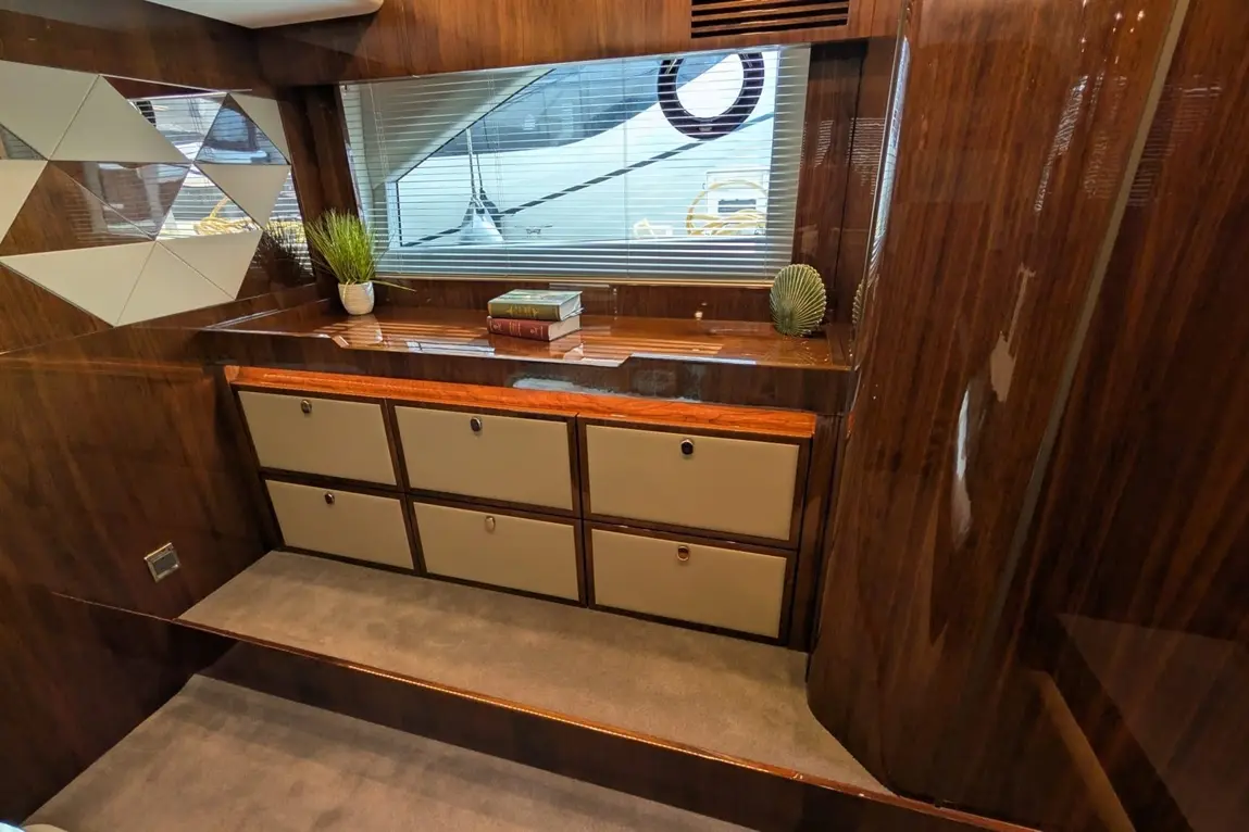 Wooden cabinet with six drawers, potted plants, books, and a mirror wall, with light filtering through blinds.