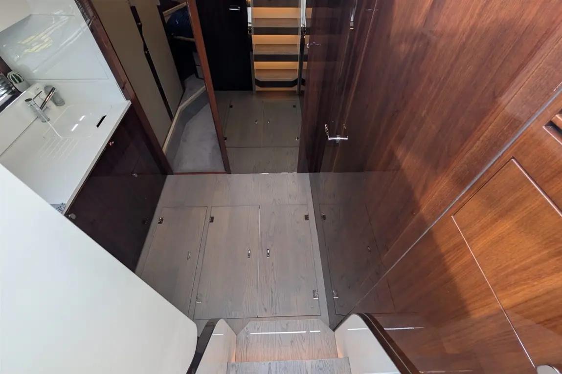 Interior view of a modern boat, featuring polished wood panels, steps, and a sleek sink area with storage.