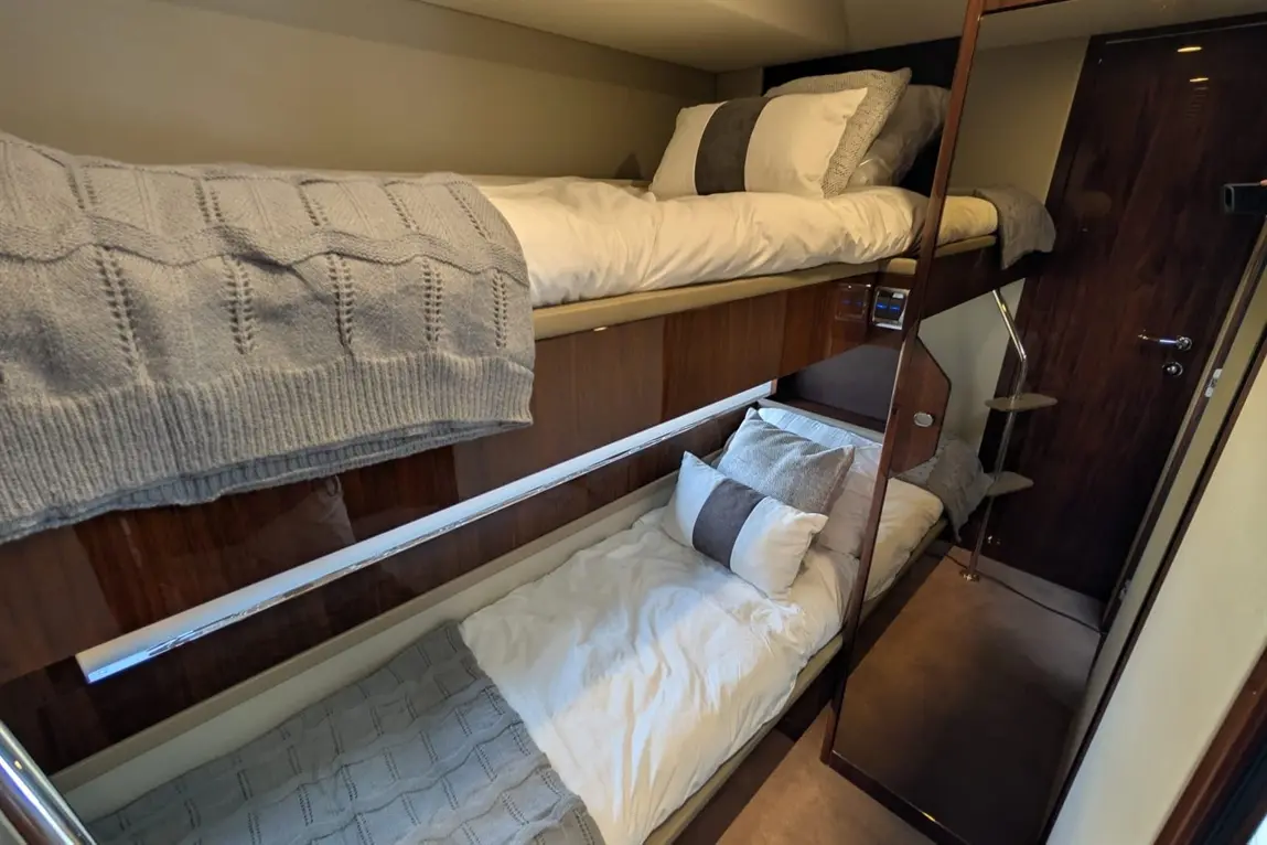 Bunk beds in a compact bedroom, featuring plush bedding, a textured throw, and a wooden door with a handle.