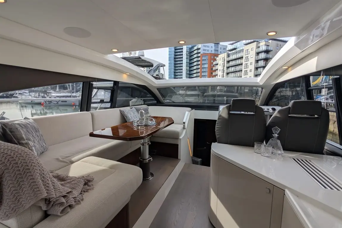 Luxurious yacht interior featuring a seating area, dining table, and modern decor with views of the marina and city skyline.