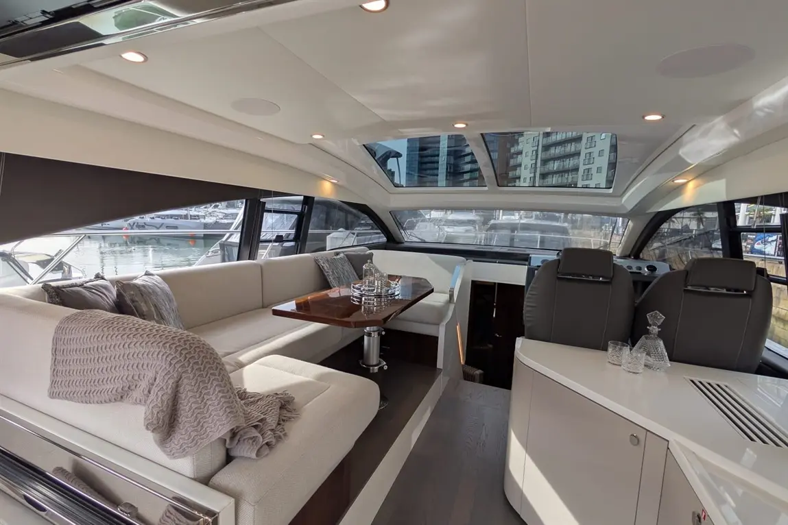 Luxurious interior of a modern yacht, featuring a spacious seating area, elegant table, and large windows overlooking the marina.