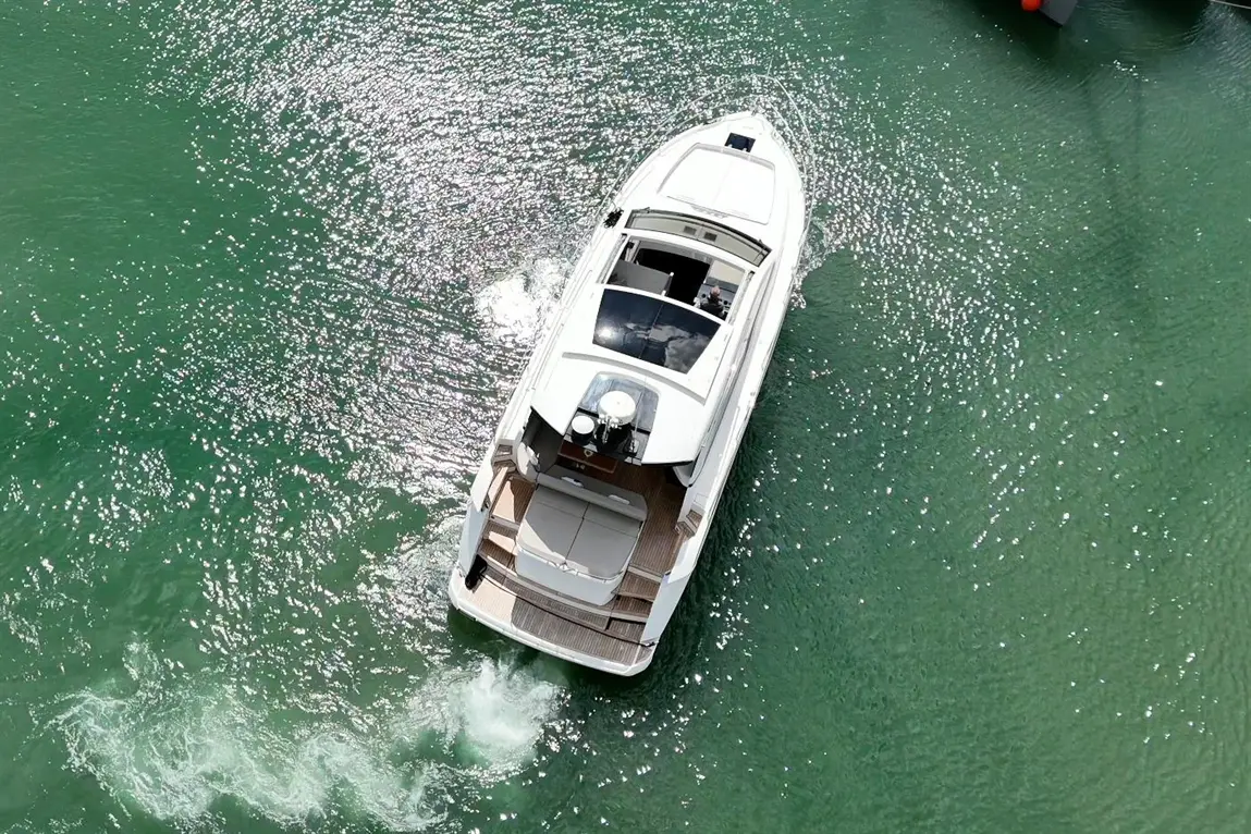 A sleek motorboat cruising on shimmering turquoise waters, leaving a gentle wake, with sunlight reflecting on the surface.