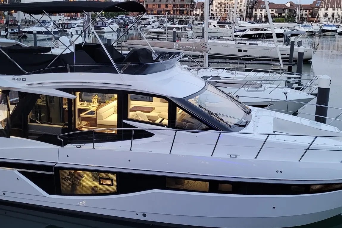 A sleek luxury yacht moored at a marina, featuring a spacious interior visible through large windows and the number "460" displayed.