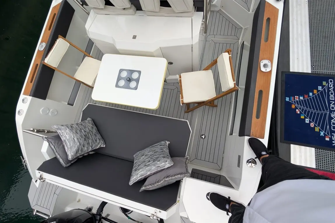 Aerial view of a boat deck with seating, table, cushions, and a "Welcome On Board" sign. Ideal for relaxation.