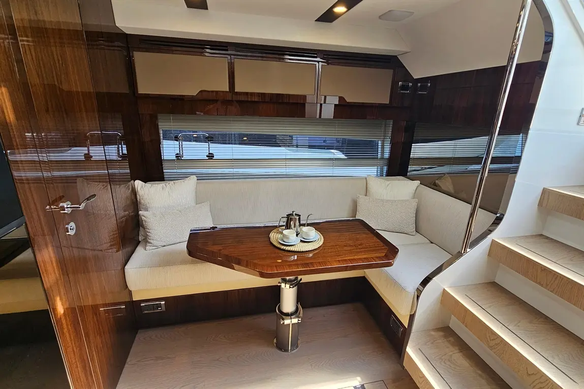 Luxurious yacht interior featuring a wooden dining table, cushioned seating, and two cups on a tray.