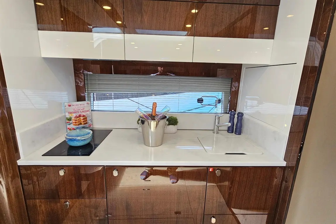 Modern kitchen with glossy wooden cabinets, a blue bowl, a silver ice bucket, and a cookbook titled "Favourite Flavours.