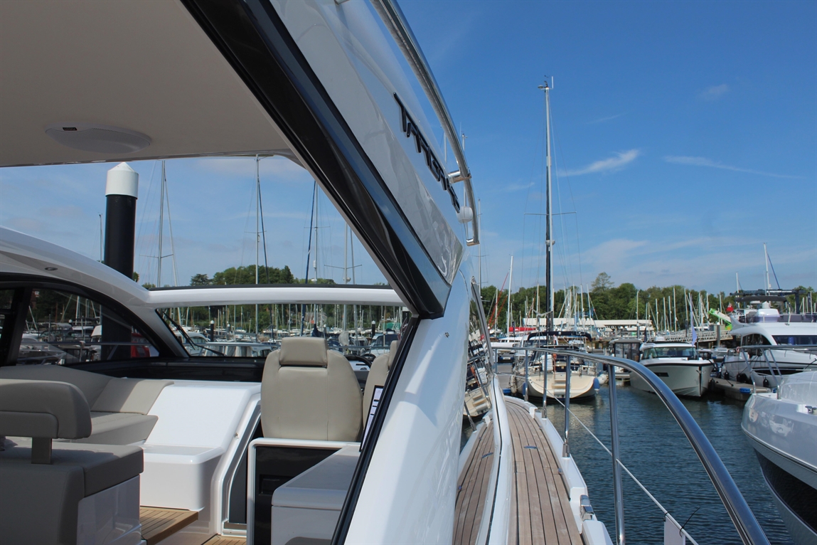 View of a luxury yacht's deck, showcasing a marina filled with boats and masts under a clear blue sky.