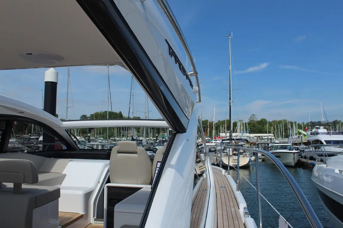 View of a luxury yacht's deck, showcasing a marina filled with boats and masts under a clear blue sky.