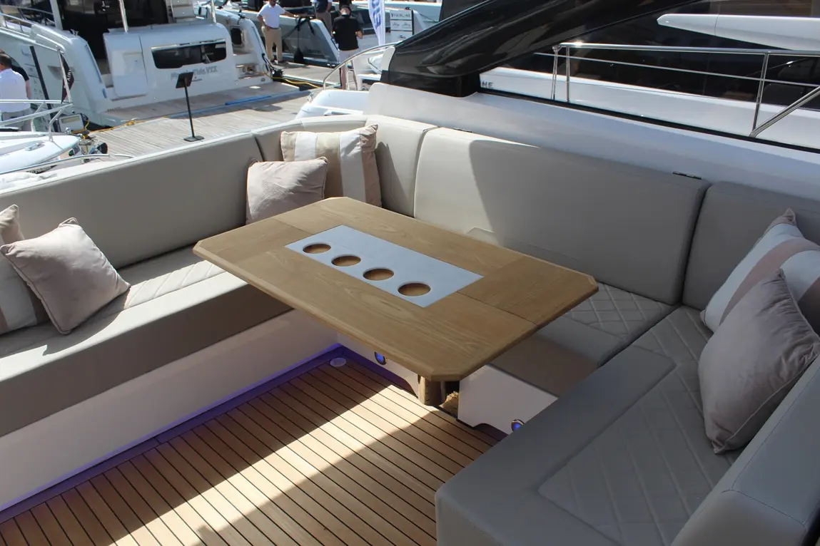 Luxury yacht seating area featuring a wooden table with cup holders, plush cushions, and a stylish deck design.