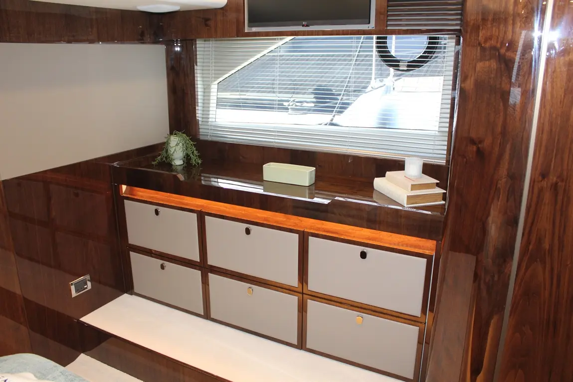 Sleek interior of a modern space featuring wooden cabinetry, drawers, a plant, a small container, and books on a shelf.