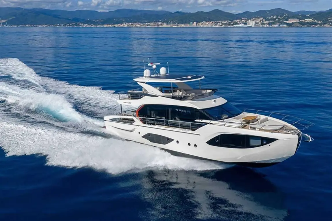 Luxury yacht cruising through calm blue waters, showcasing sleek design and elegant features against a scenic coastal backdrop.