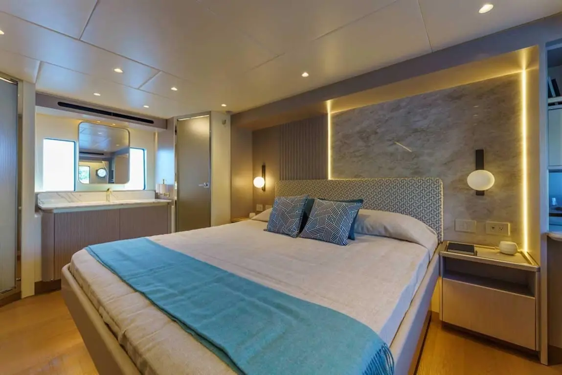 Modern bedroom featuring a double bed with blue throw, decorative pillows, ensuite bathroom, and ambient lighting.