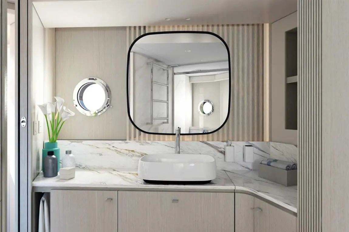 Modern bathroom with a marble countertop, oval mirror, vessel sink, green plant, and circular window. Elegant and spacious design.