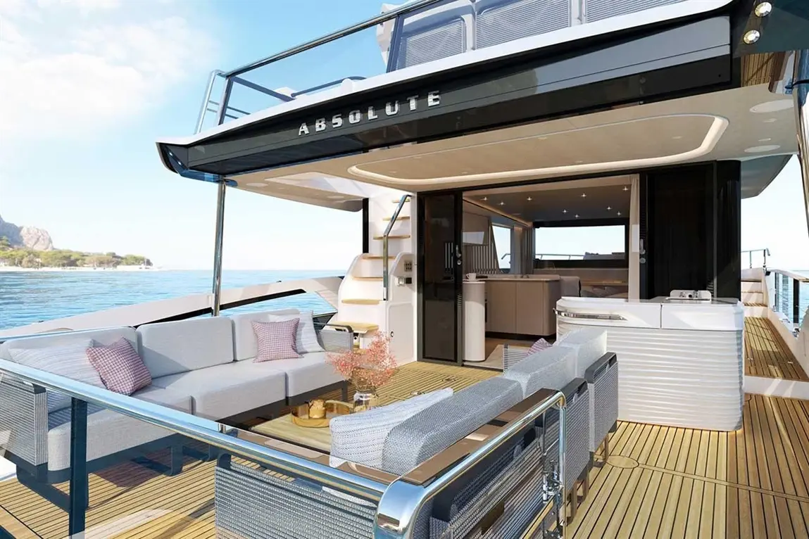 Luxury yacht deck featuring a spacious lounge area with grey sofas, a glass table, and a view of calm waters. "ABSOLUTE" logo visible.