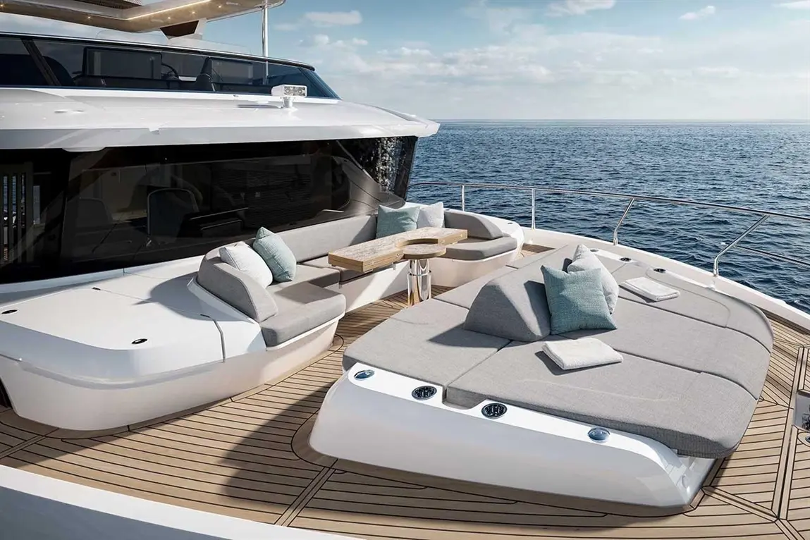 Luxury yacht deck featuring stylish seating areas, cushions, and a wooden table, overlooking tranquil ocean waters.