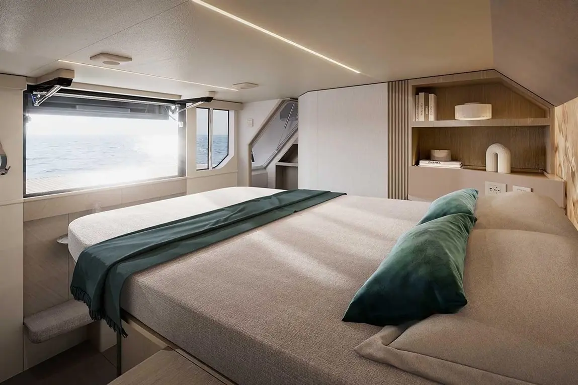 Modern cabin interior with a double bed, green throw, large windows showing sea views, and stylish shelves.