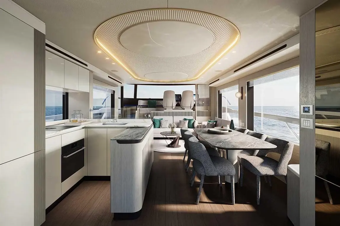 Modern yacht interior featuring a sleek kitchen, dining area with grey chairs, and panoramic ocean views through large windows.