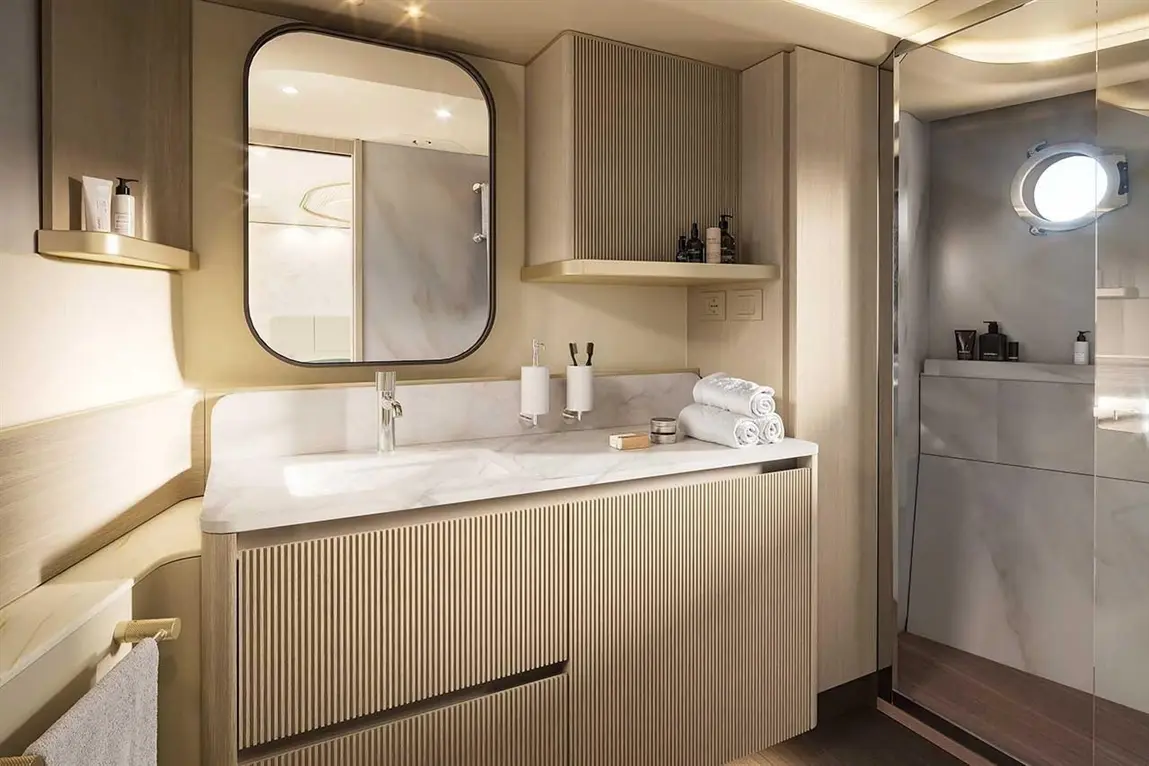 Modern bathroom featuring a marble sink, wooden cabinetry, neatly folded towels, and a shower with a glass door.