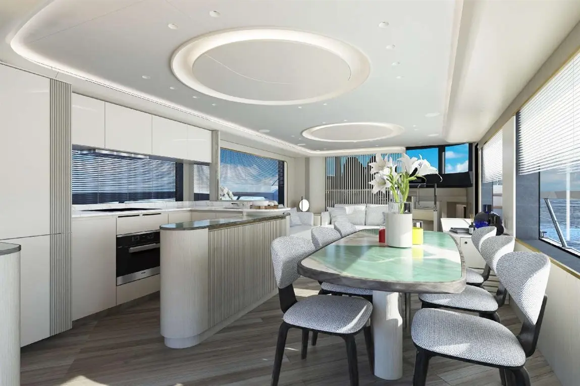Modern yacht interior featuring a spacious kitchen, elegant dining table, and large windows with scenic views.