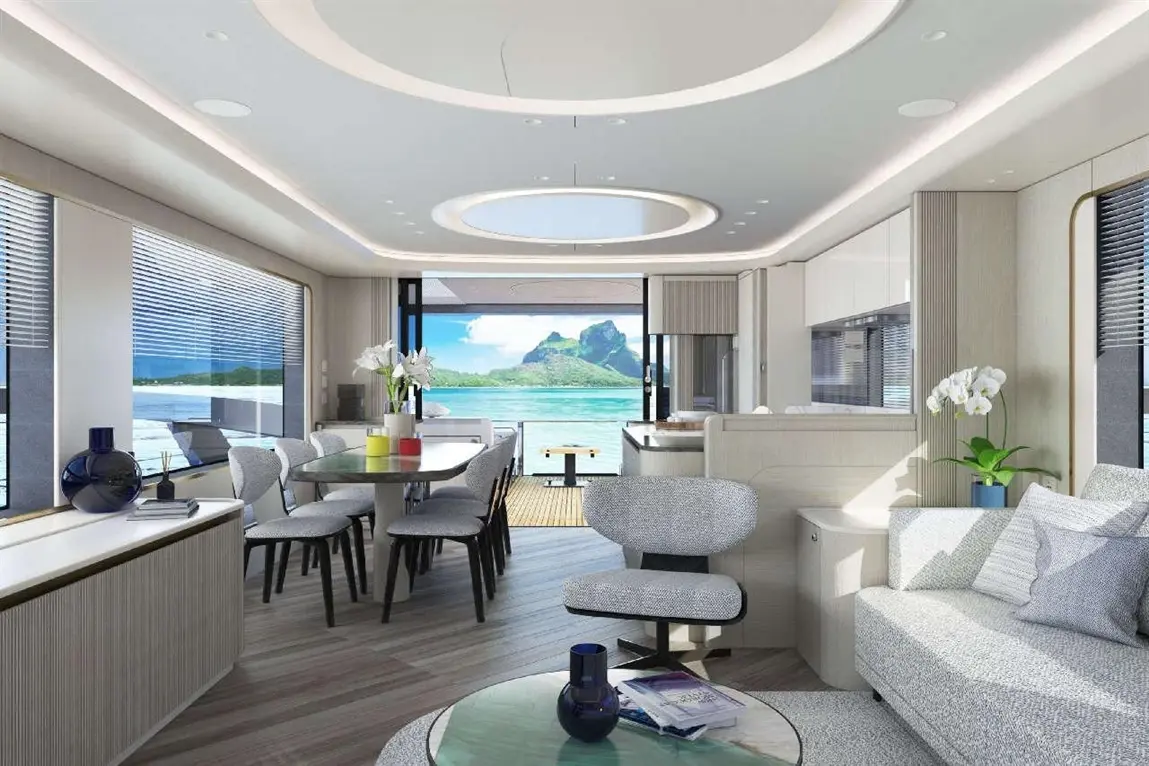 Modern interior showcasing a dining area and lounge with ocean view, featuring a glass table, stylish chairs, and indoor plants.